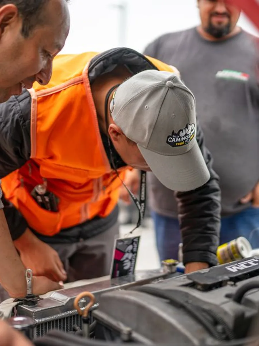 Des mécaniciens examinent un moteur, capot ouvert, dans l'atelier de la rédaction.